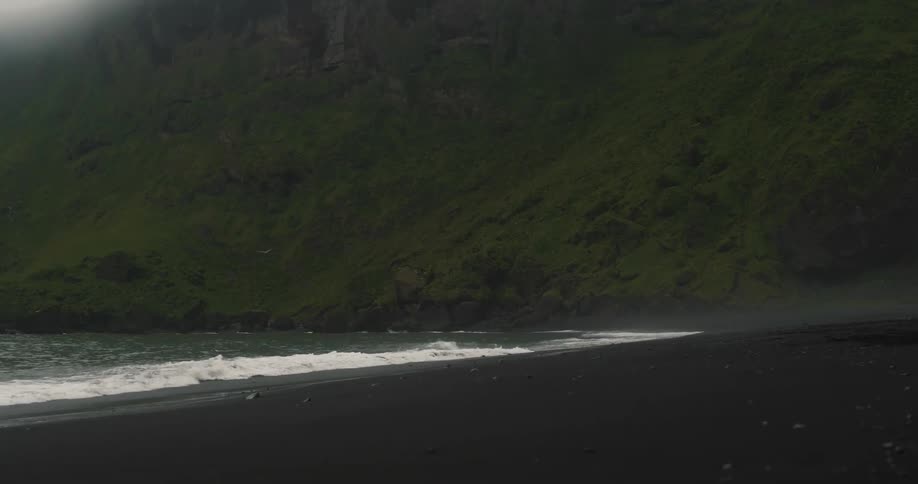 Waves crash on the shore by the mountain