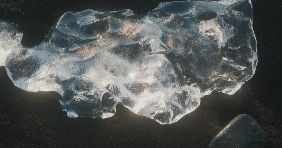 Chunk of ice melts on the ground and reflects the light