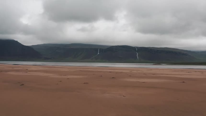 A mountain and beach surround the water