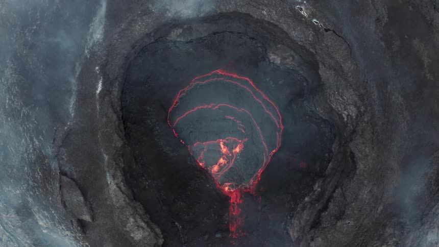 Aerial panorama of a crater amidst lava and smoke