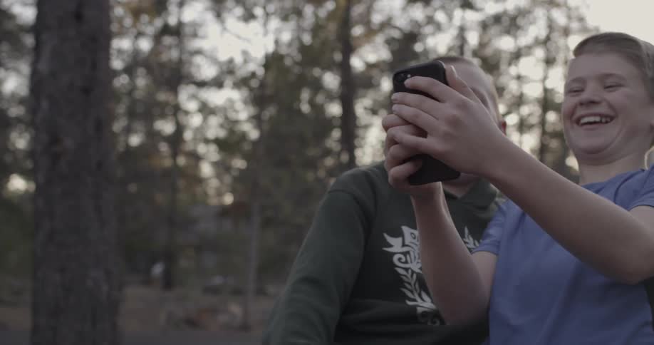 Two boys laugh at what they see on a phone
