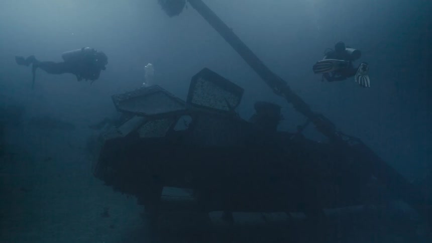 Merg divers underwater amidst wreckage