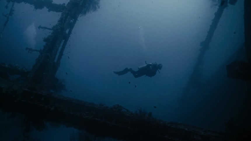 A diver underwater next to a sunken ship