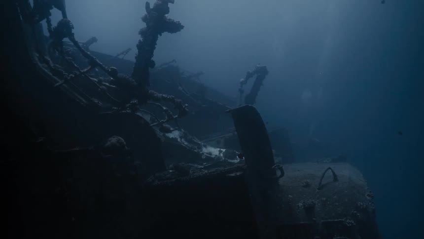 Diver heading towards wreckage at the bottom of the sea
