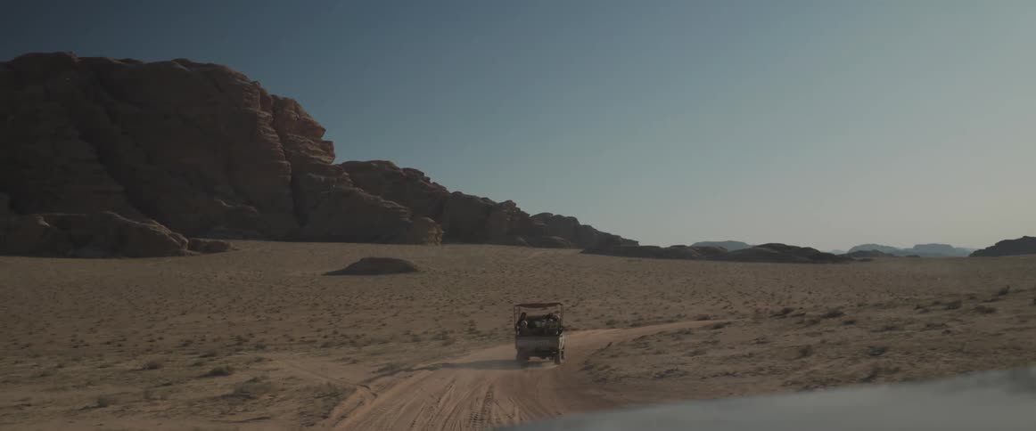 Cars driving on the ground around a valley with a cloudless blue sky