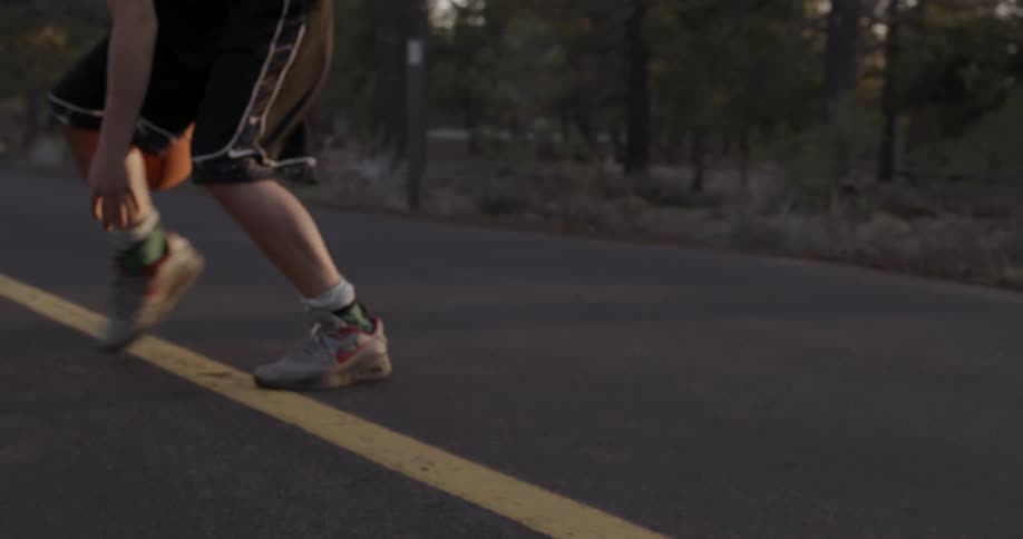 A man dribbles a basketball through and behind his legs on the asphalt