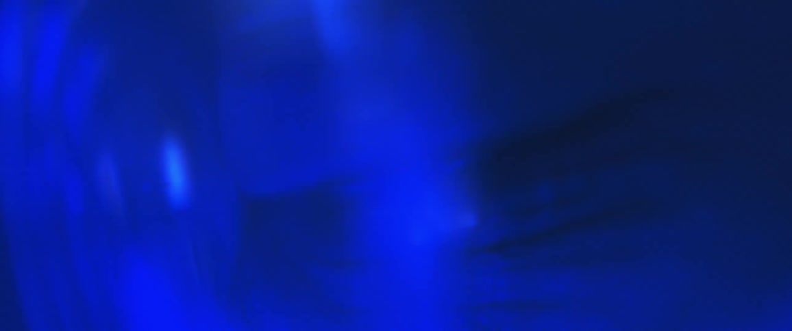 Close up of persons eye looking through glasses under blue lighting