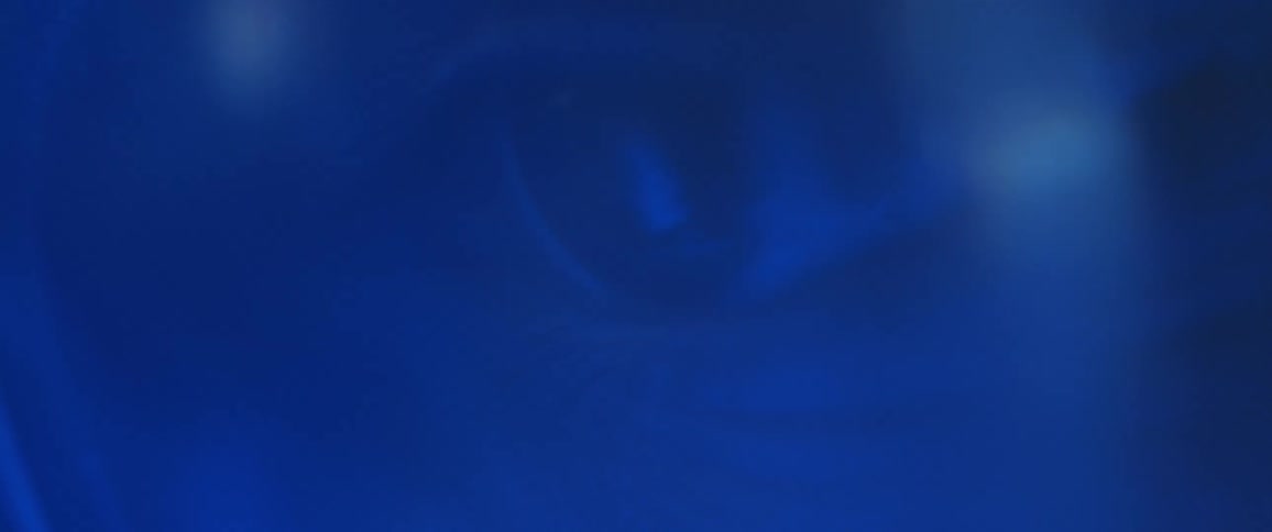 Extreme closeup of a mans eyes with protective glasses and reflective blue electric lights