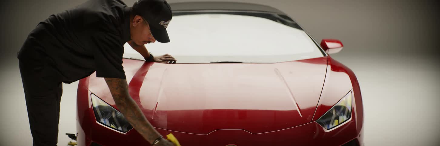 A man cleaning a car with a yellow cloth