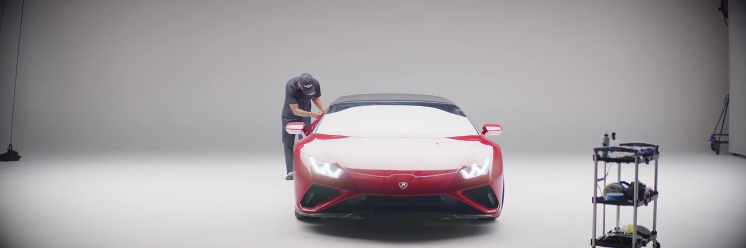 A man examining a luxury car parked in the garage