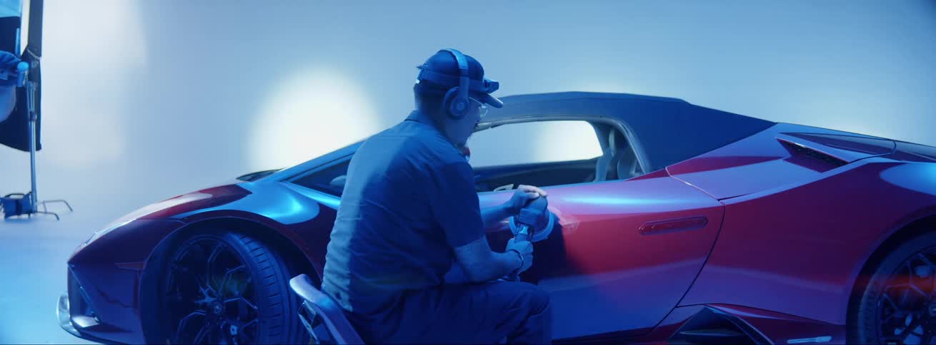 Man polishing the side of a red ferrari