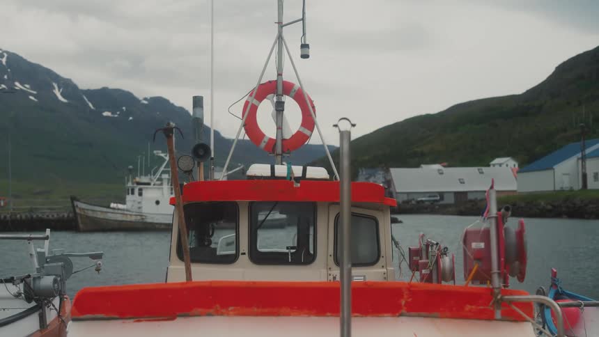 Boats docked in the sea at docks with a chain of mountains in the background