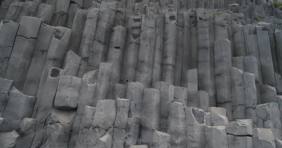 Twisting basalt sea wall rock stacks on a volcanic black beach in iceland