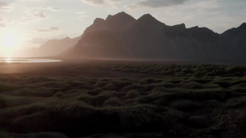 Panorama of the ground with moss by the sea and a mountain range ahead on a morning