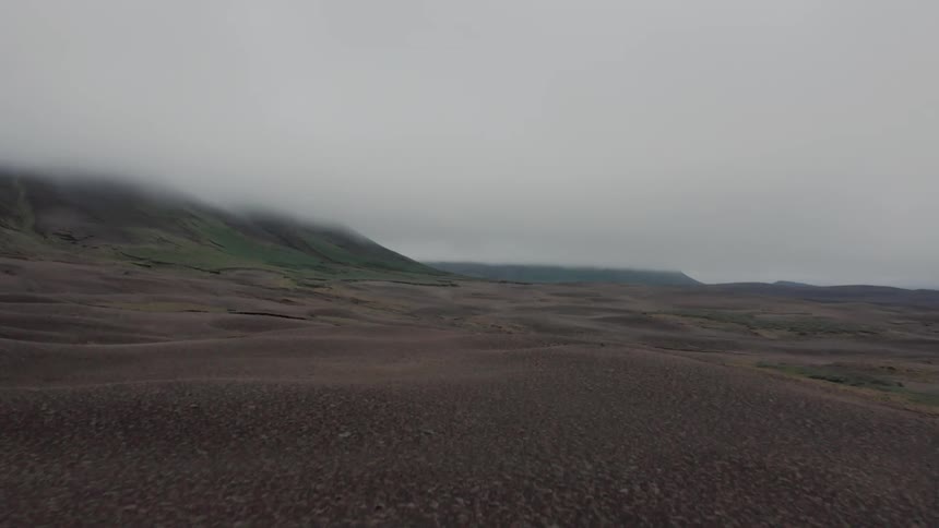 Aerial panorama of a terrain amidst a mountain range on a cloudy and misty day