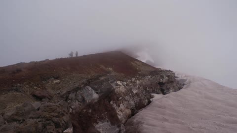 Group of people walk along a fog covered mountain