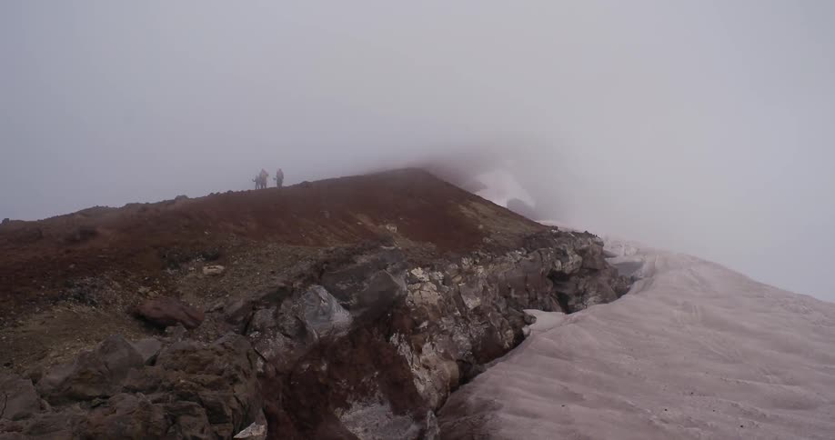 Group of people walk along a fog covered mountain