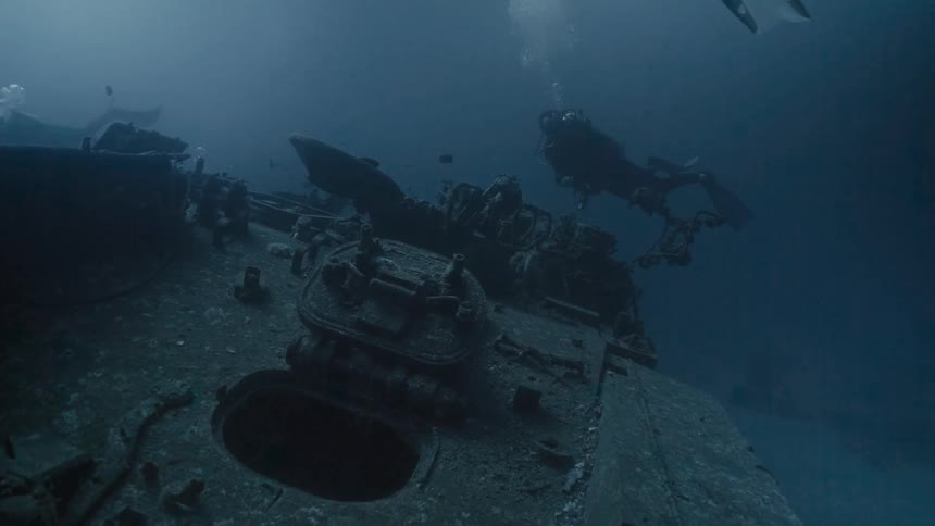 Group of divers at the bottom of the sea amidst wreckage