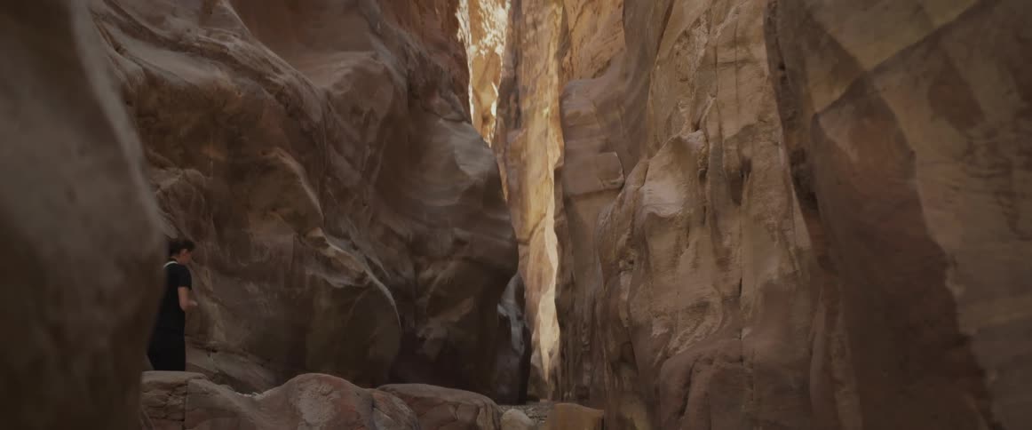 Woman walking with her back turned climbing rocks amid valleys