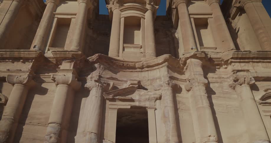 A woman slowly walks away from a massive ancient temple