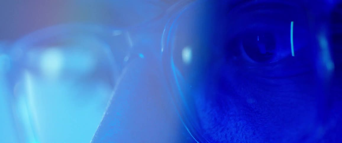 Extreme closeup of a mans face wearing protective glasses with a reflection of light