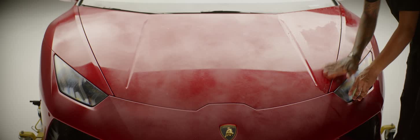 A man running his hands on the hood of a red lamborghini