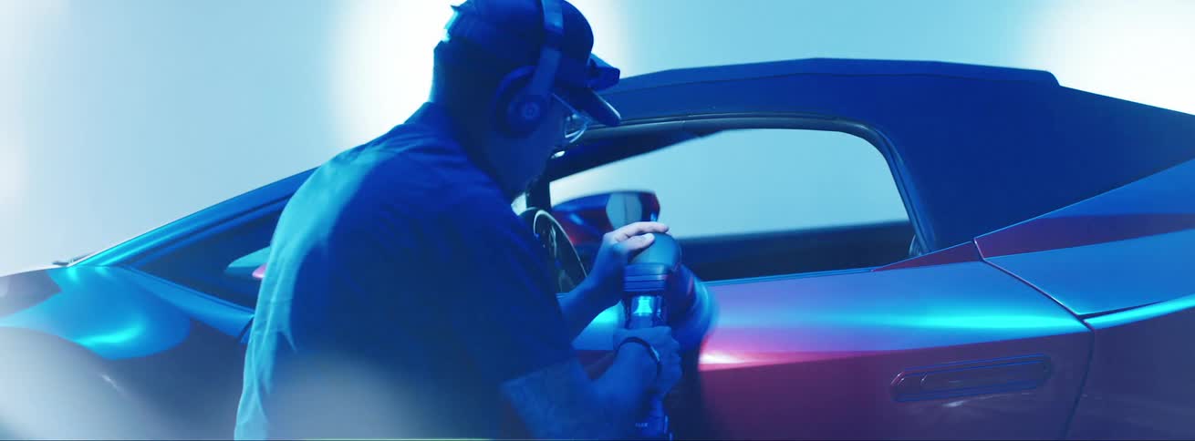 Man polishing the door of a red lamborghini inside a showroom with lights