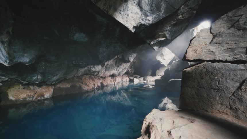 A cave with many rocks and still crystal clear water