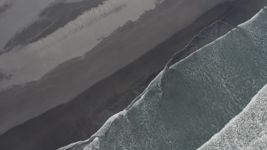 An aerial view of waves crashing on the beach sand