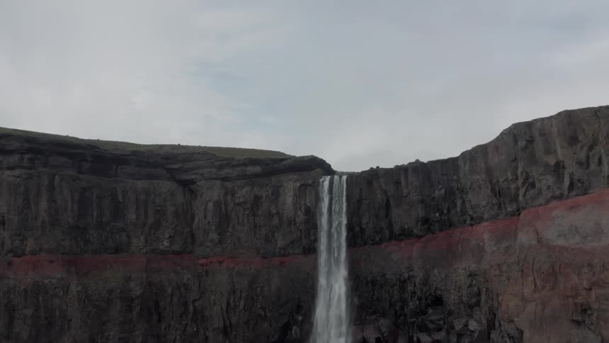 A waterfall is on the mountain pouring off the cliff