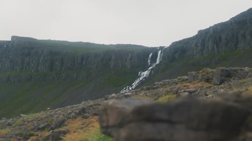 A waterfall flows down a rocky cliff into the canyon below