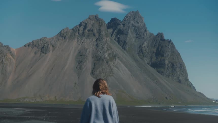 A woman walking towards the mountain during the day