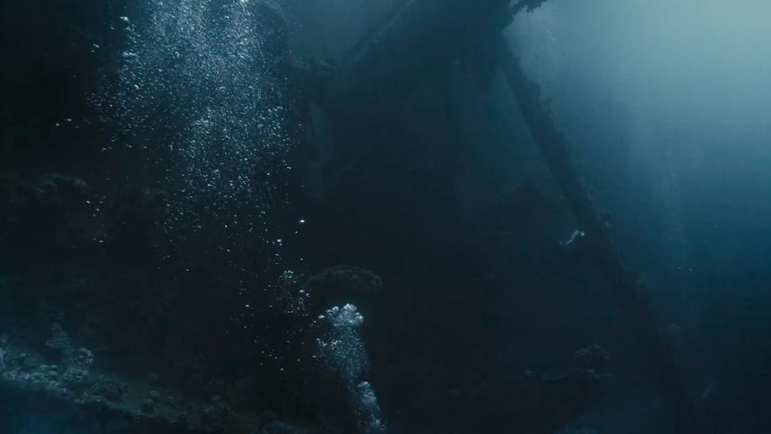 Divers at the bottom of the sea amidst a shipwreck