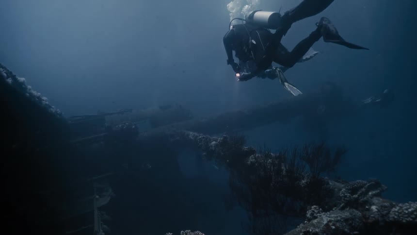Divers exploring a ship at the bottom of the ocean