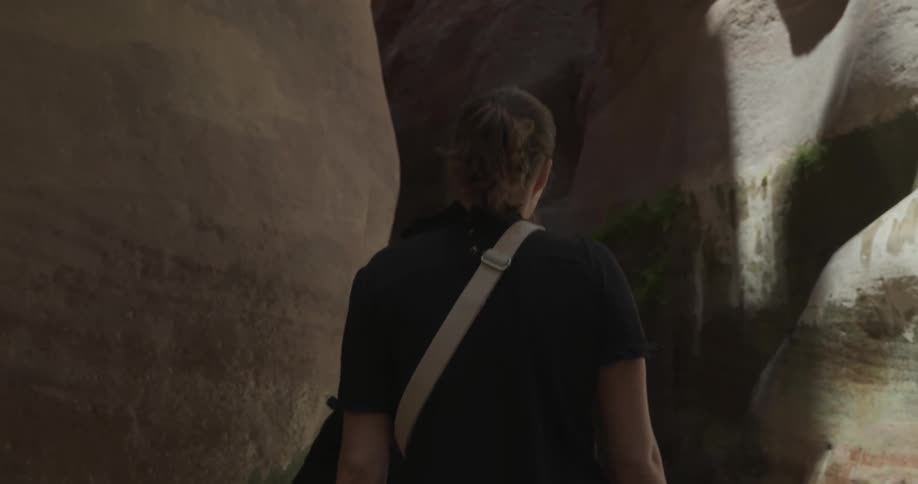 Woman walking away on a path in the midst of a valley