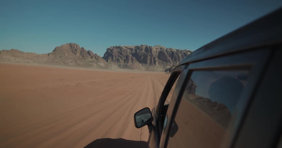 Someone is driving a black van in the desert on a sunny day