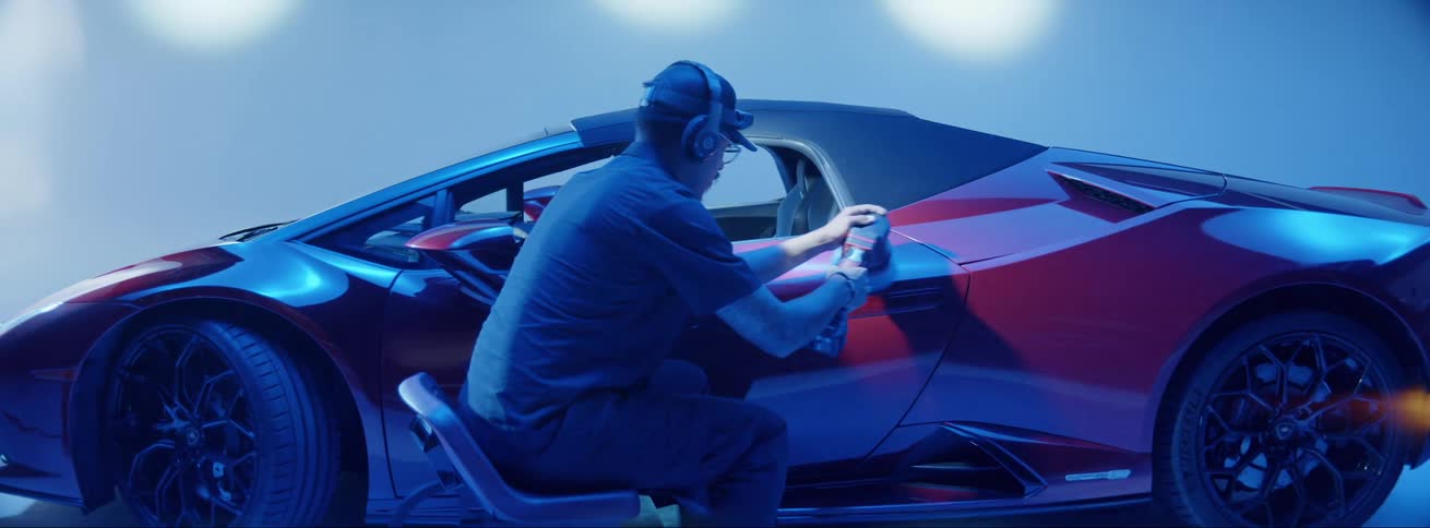 A man polishing a luxury car in a dark garage