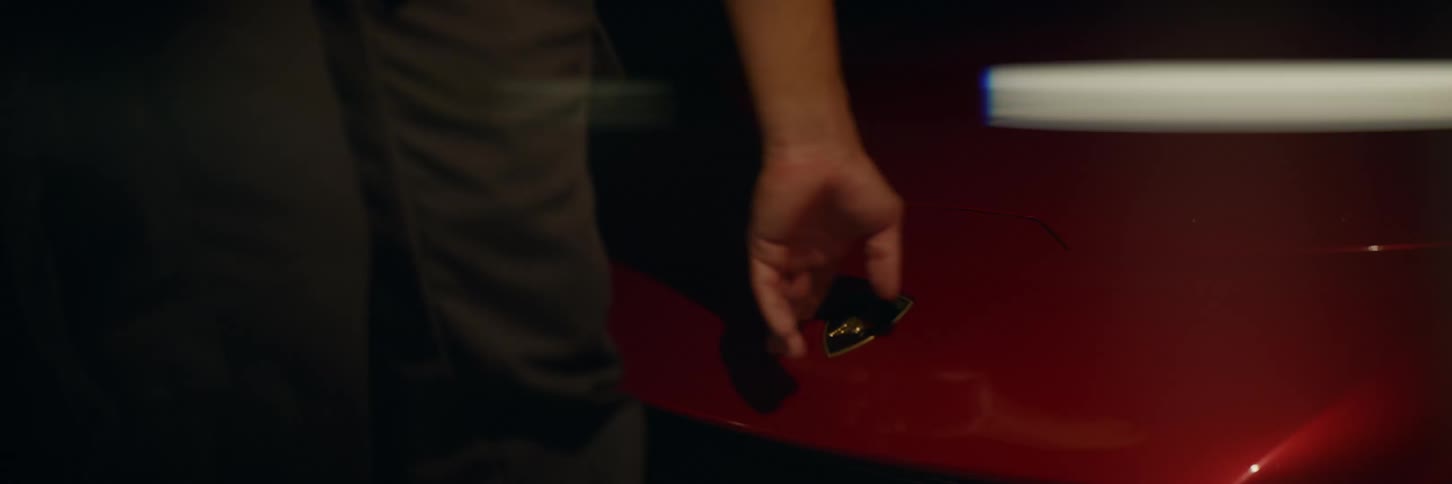 A lamborghini is on a turn table and a finger runs over the hood