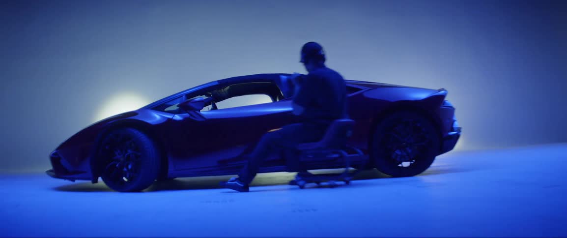 Man sitting in a chair with a polisher beside a lamborghini