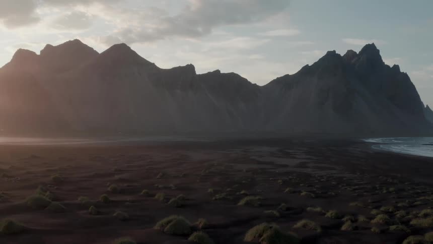 Small mounds cover beach bordering craggy mountains on a foggy day