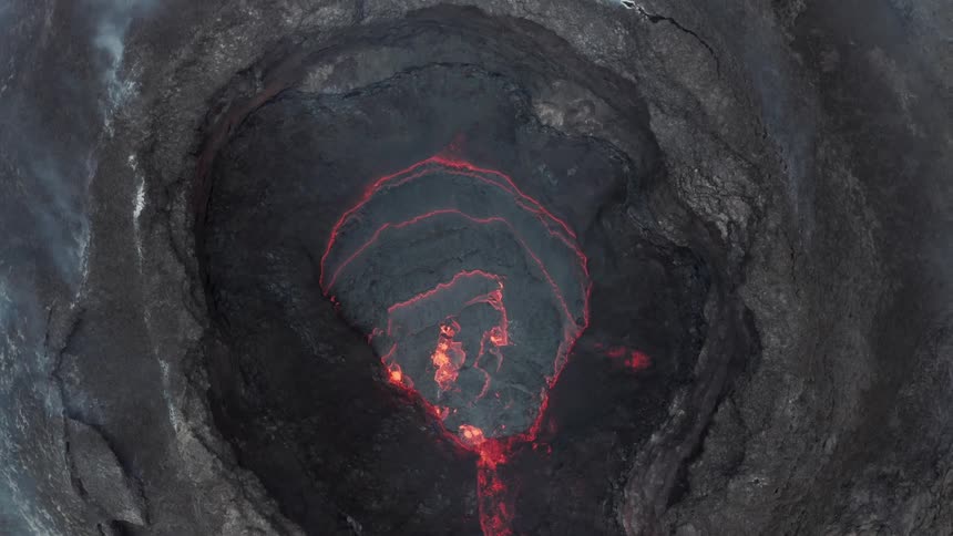 Looking down into a volcano we can see glowing redhot lava and wisps of smoke