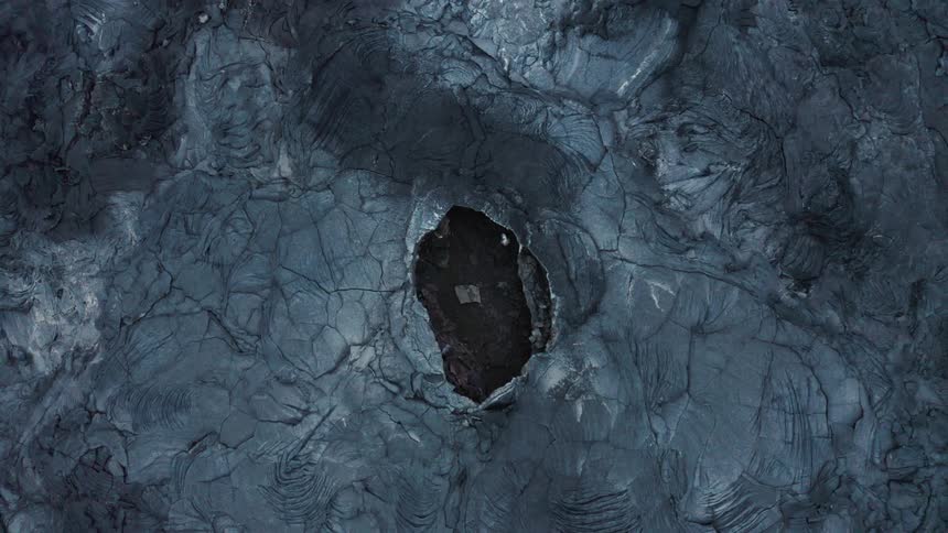 A dark hole in an arid textured stone floor