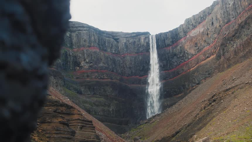 A tall waterfall pours over a steep cliff