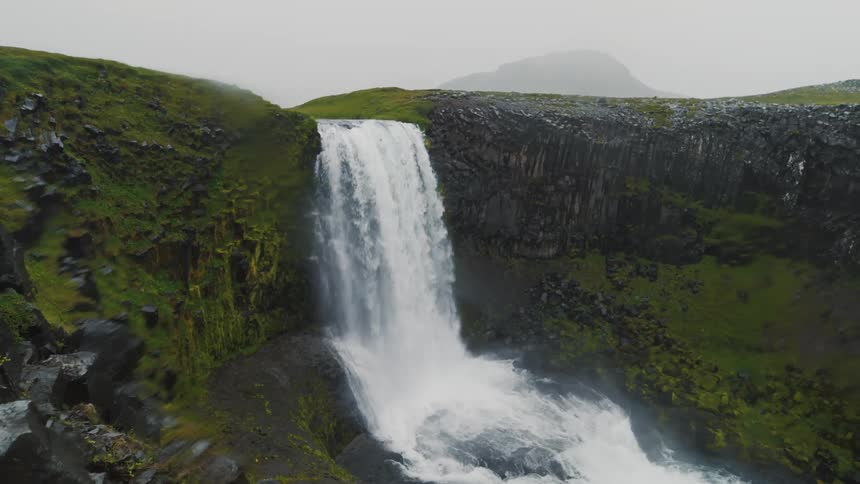 Aerial panorama of a waterfall in strong free fall on a cloudy day