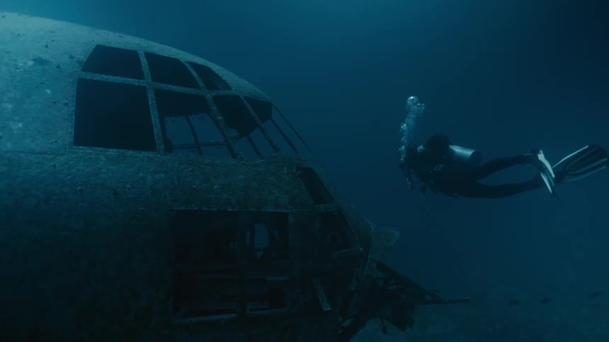Scuba diver swimming around a sunken plane in the ocean