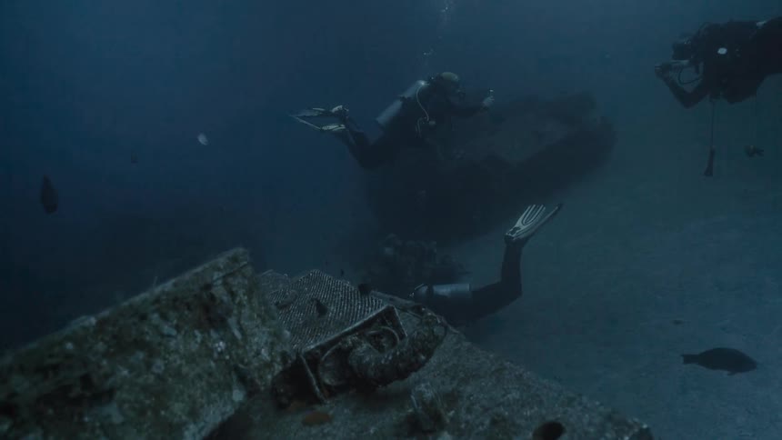 View from inside the sea with divers amidst sunken tanks