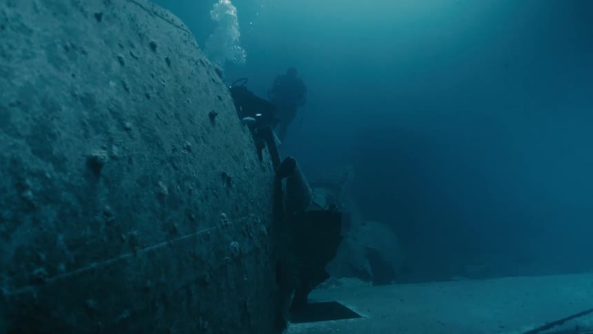 Scuba divers inspect a sunken plane on the sea floor