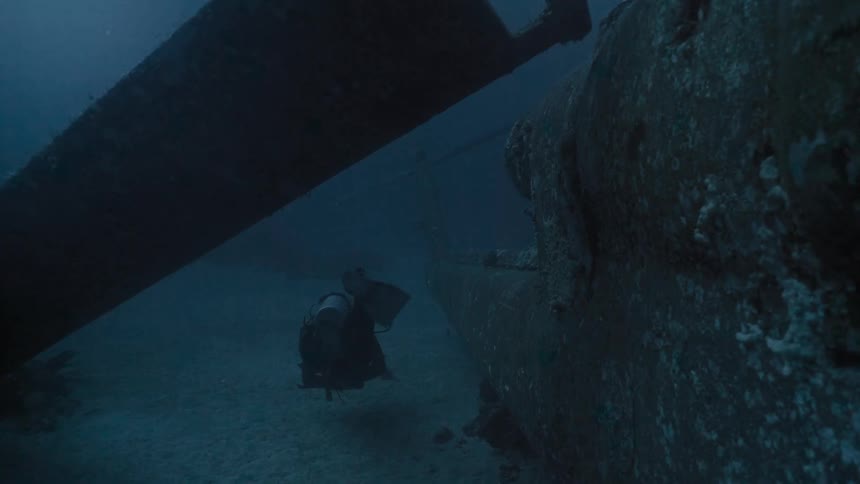 Divers exploring a vessel at the bottom of the ocean