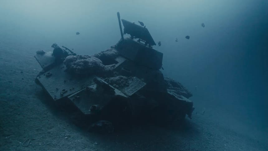 Sunken tank on the ocean floor surrounded by fish