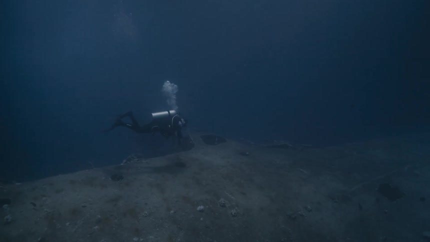 Diver at the bottom of the sea under wreckage